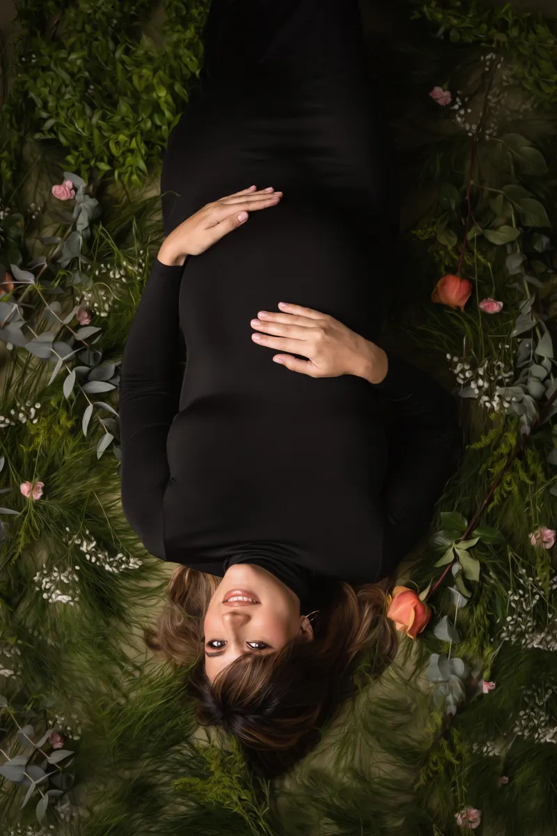 Embarazada recostada entre plantas y flores