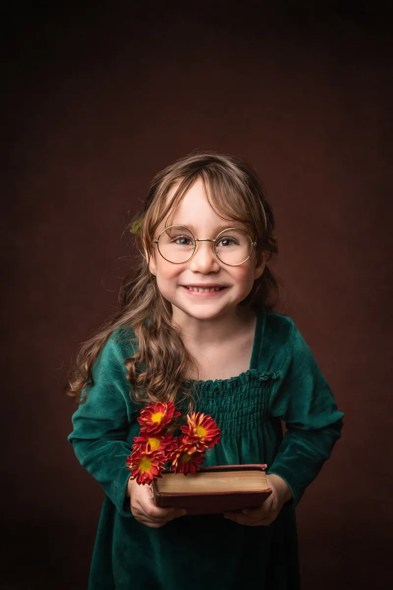 Niña sonriente con lentes y flores