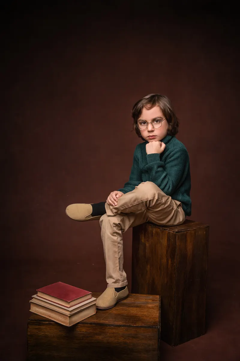 Niño sentado sobre cajas de madera con libros
