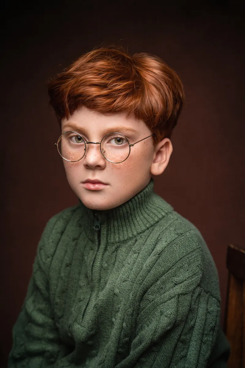Niño pelirrojo con lentes y suéter verde