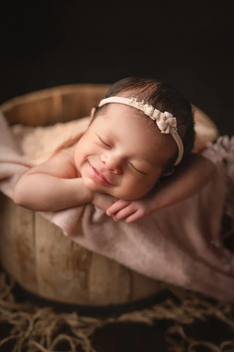 Recién nacida sonriendo dormida en una canasta