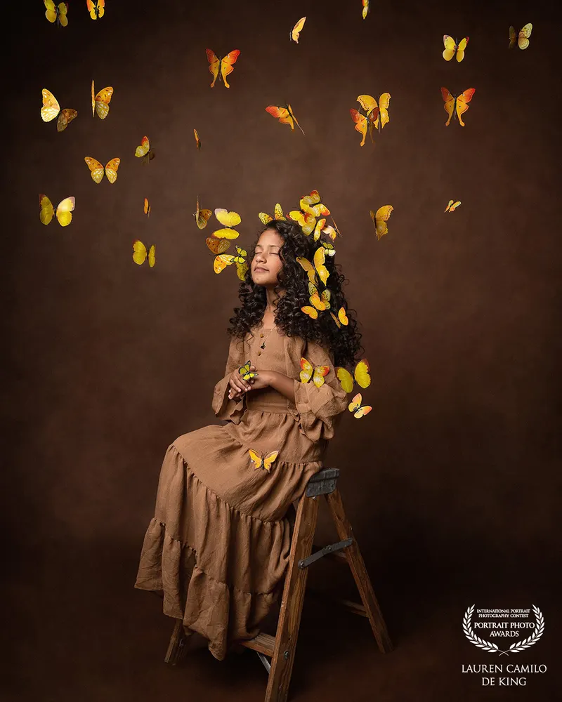 Niña con vestido marrón rodeada de mariposas amarillas