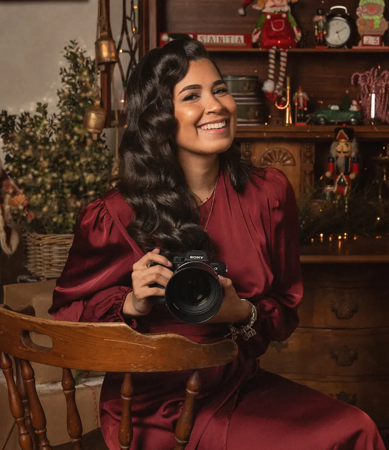Lauren King sonriendo con su cámara en el set navideño